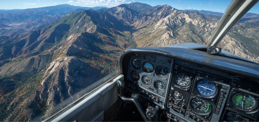 View from airplane cockpit showing dashboard instruments and mountain landscape for how to read altimeter