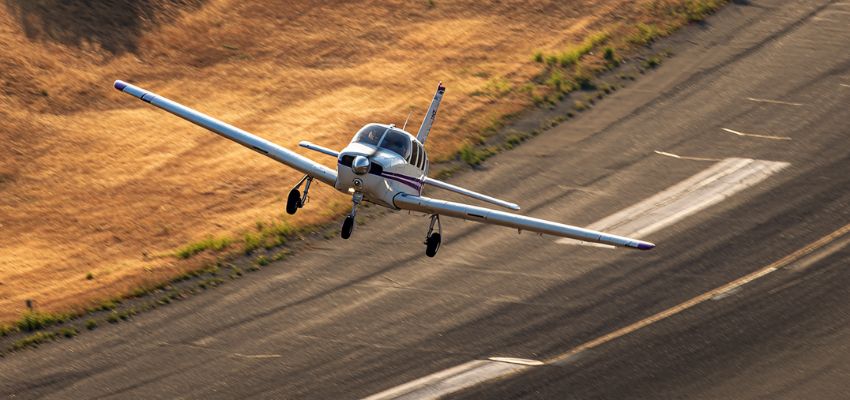 Small single-engine airplane taking off or landing on runway, viewed from side, demonstrating coordinated flight principles to avoid slip vs skid in turns.