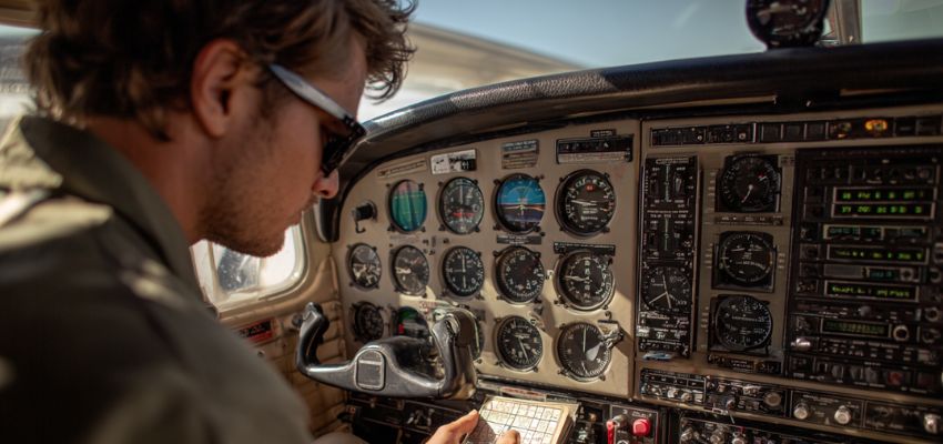 Pilot checking instruments in cockpit, demonstrating awareness of magnetic compass errors in aviation